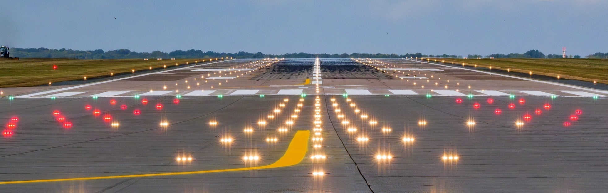 Start- und Landebahn mit beleuchteten Markierungen und gelber Fahrbahnmarkierung unter bewölktem Himmel